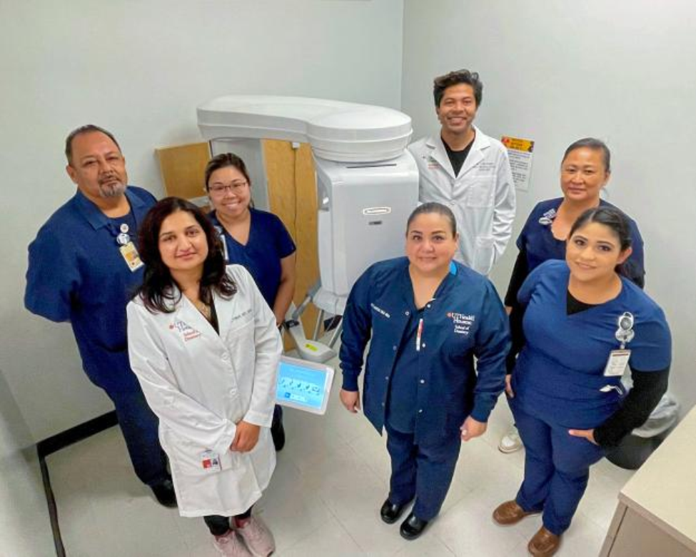 Overhead group photo standing around a cone-beam computed tomography system.