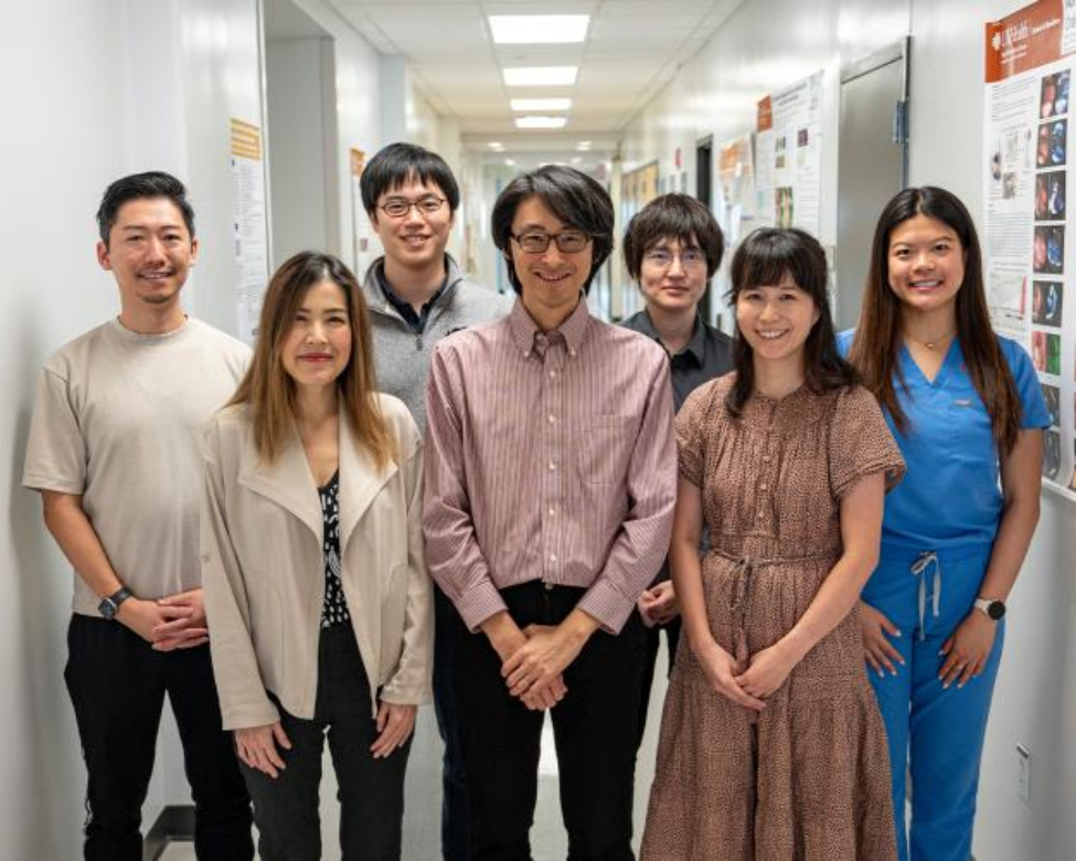 Seven people stand shoulder to shoulder in a hallway.
