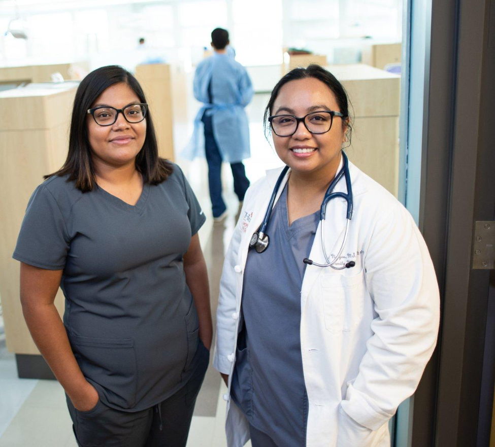 UT Physicians Medical Assistant Thalia Quintanilla (left) and Nurse Practitioner Rachell Nguyen, NP-C, RN, stand outside a treatment room at the School of Dentistry.
