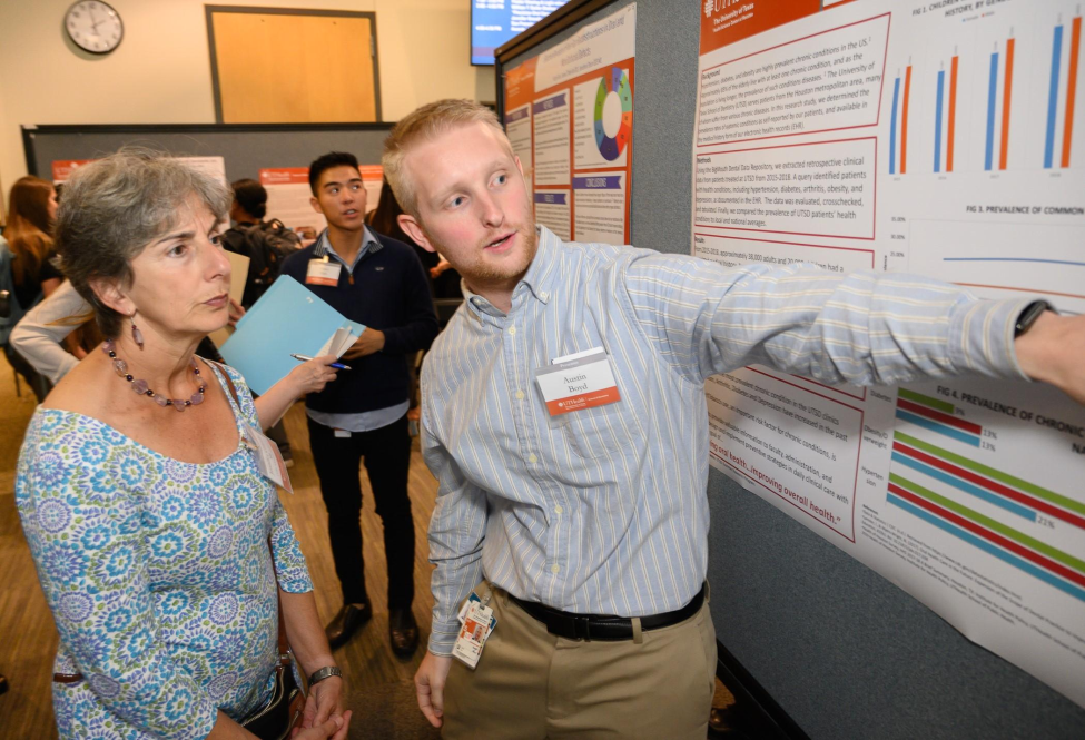Dr. Jennifer Grandis, guest speaker at the Student Research Showcase, listens as dental student Austin Boyd describes research he participated in over the summer.