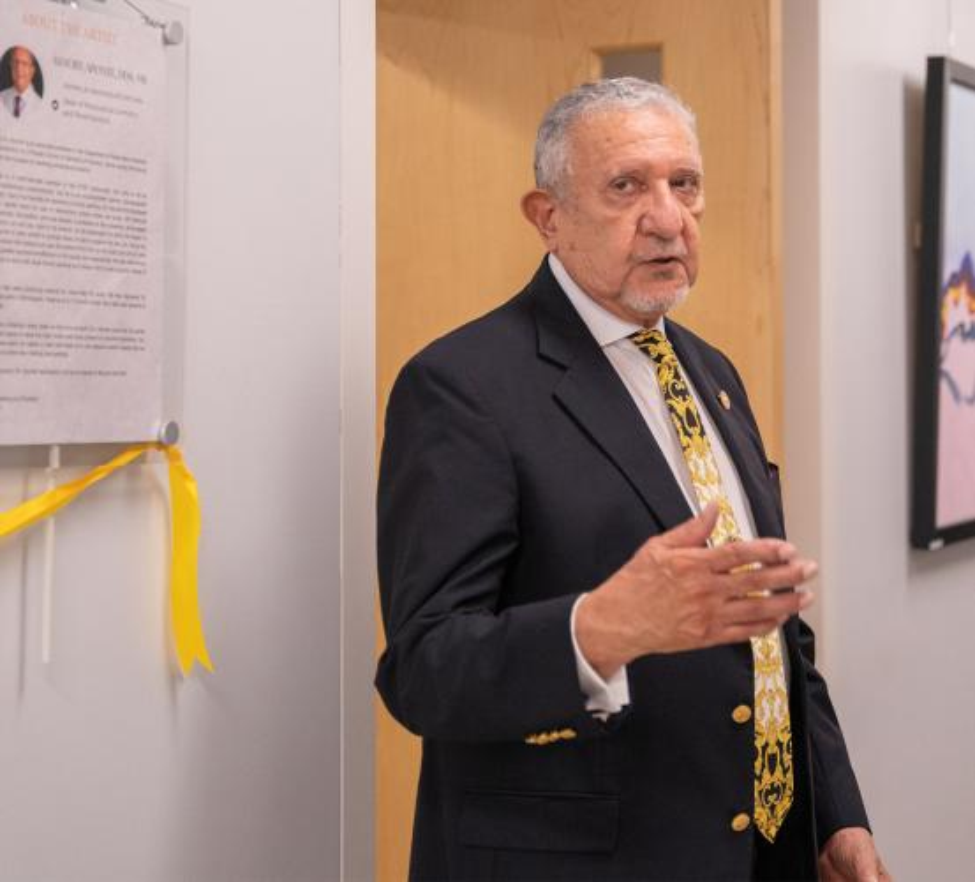 A man gives remarks in front of a ceremonial ribbon.