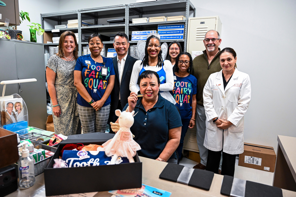 Everill Marcano surrounded by Dean John A. Valenza, DDS, and other members of administration and the Office of Patient Care.