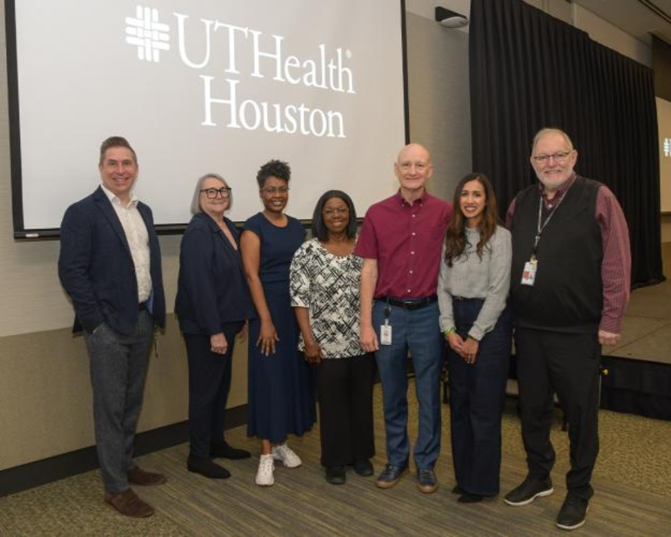 Group photo of faculty members next to a stage.