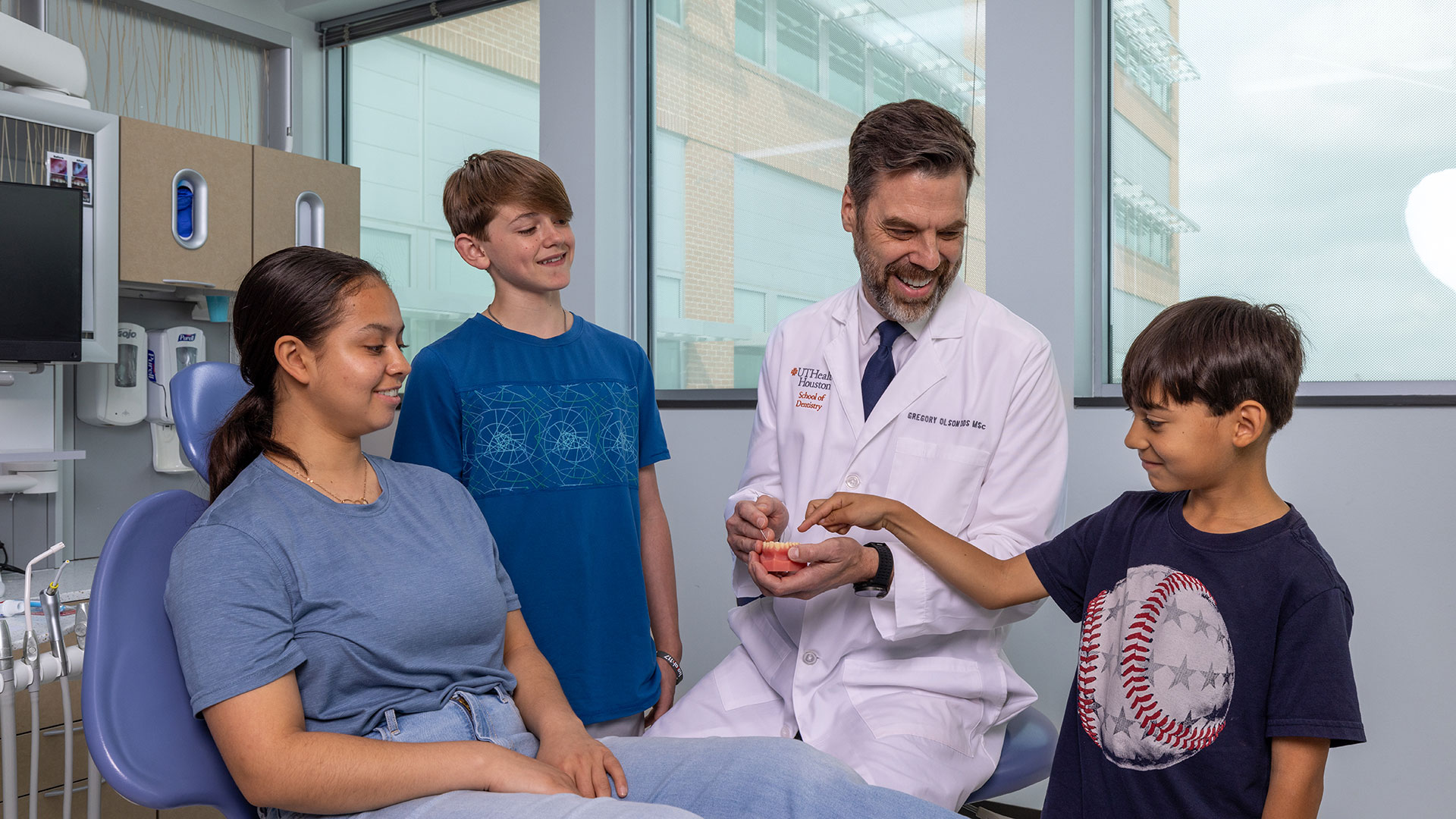 A dentist in a white lab coat meets with a woman and two children
