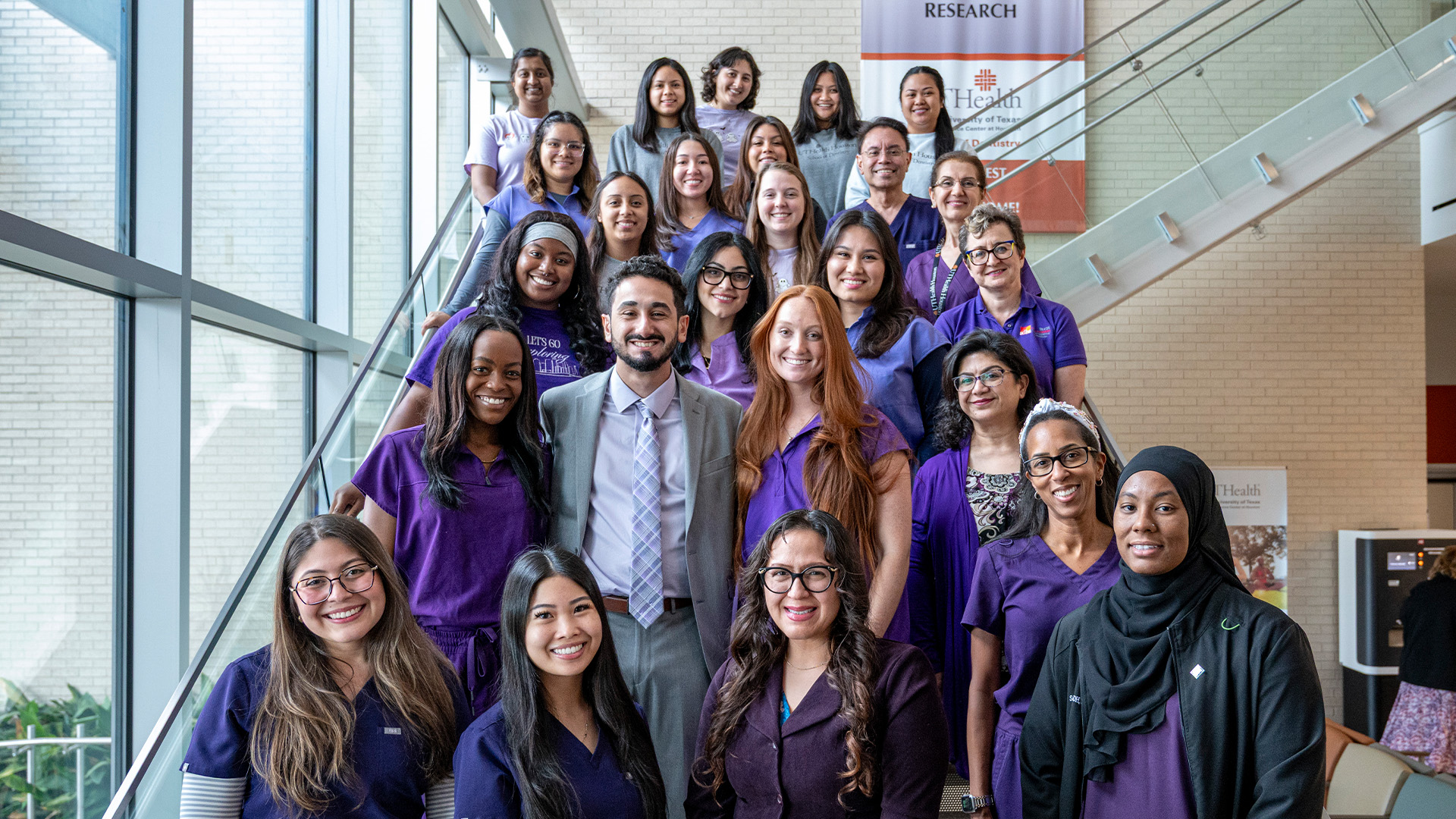 A group of dental hygiene students and faculty pose together on a staircase inside the School of Dentistry.